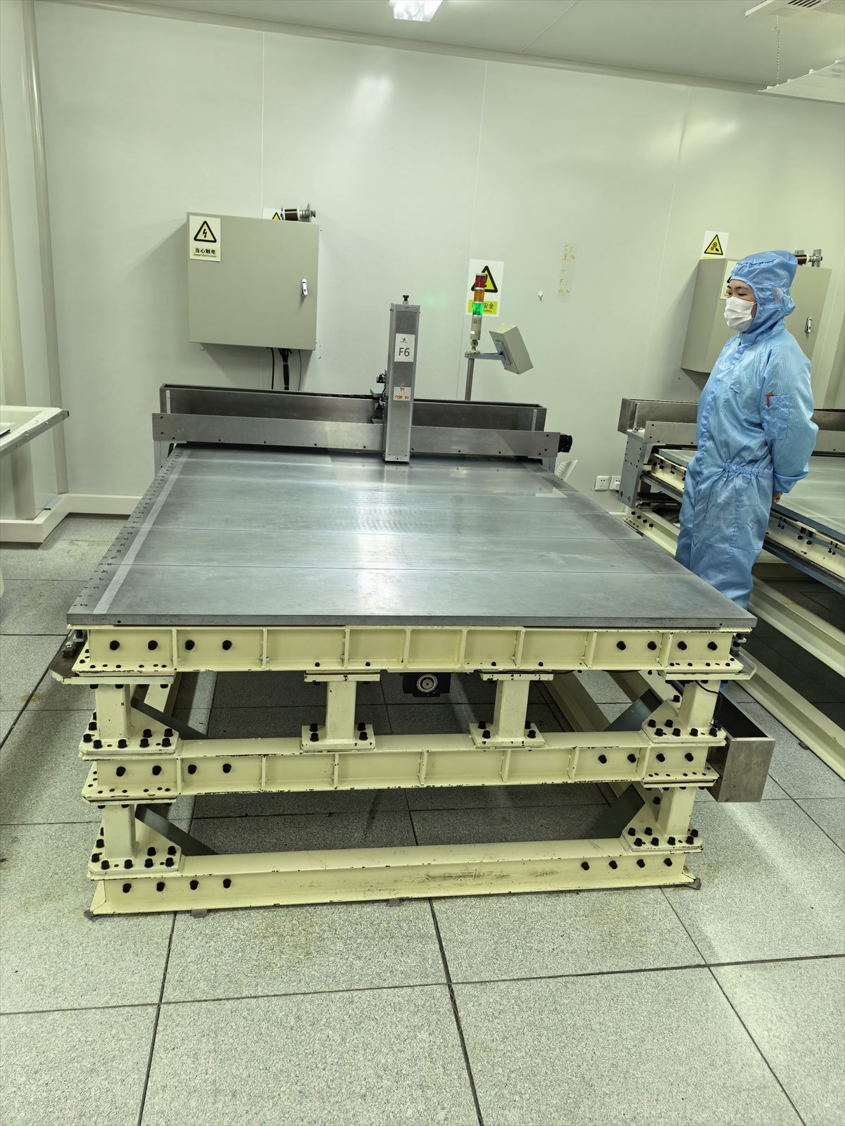 DRWO operator inspecting a large-format ultra-fine-wire laying machine used for functional film OEM production